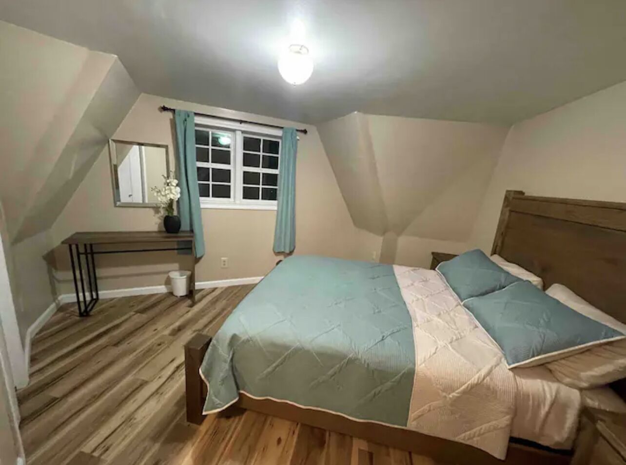 Un dormitorio con cama, escritorio y ventana con cortinas.