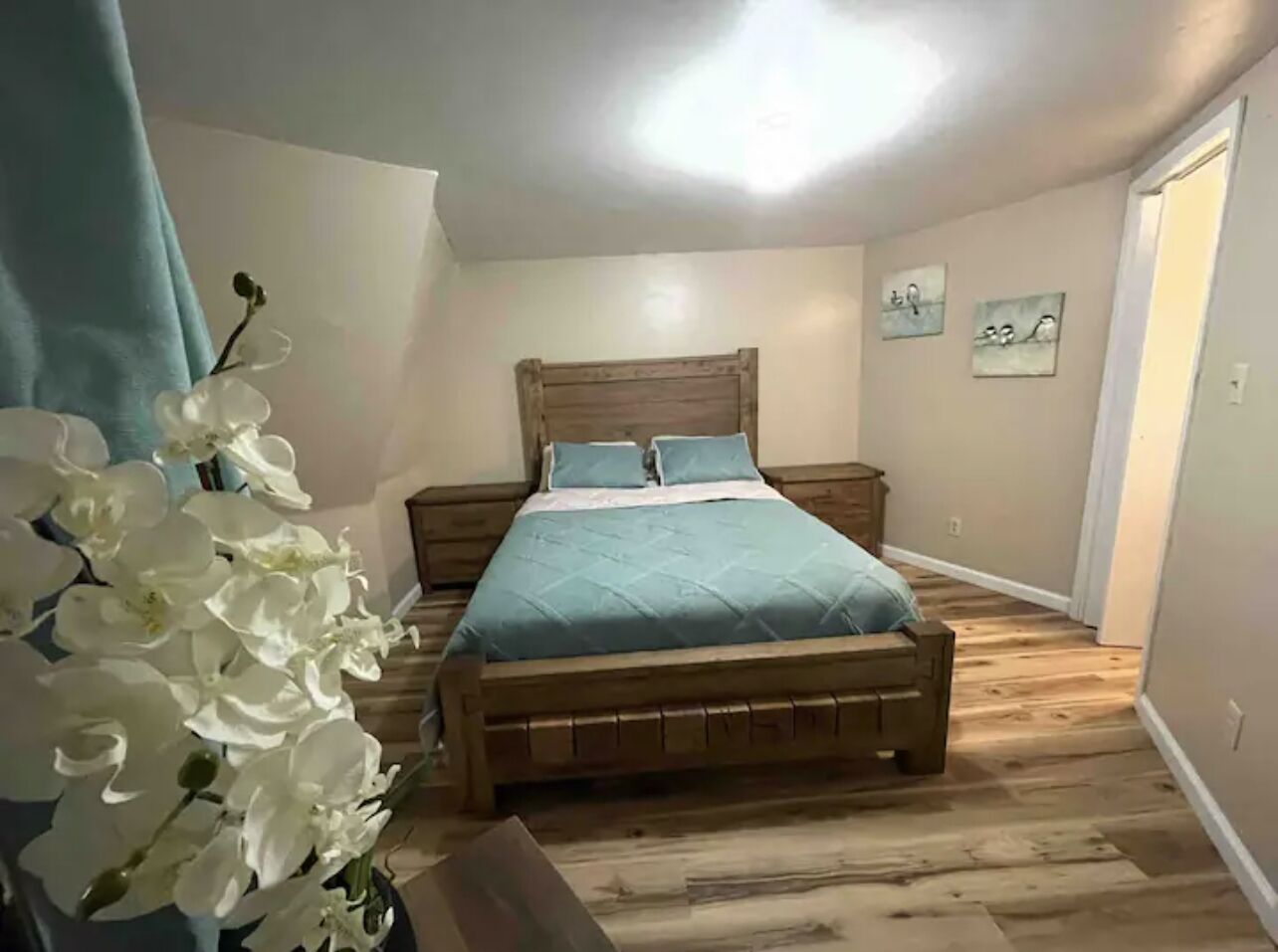 Una camera da letto con un letto di legno, un comodino e una mensola a parete.