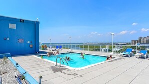 A rooftop pool area with clear blue water, lounge chairs, and a view of the ocean and buildings in the background. - 🏖️Serene Bayfront Bliss - Pristine 3 Bed/3Bath condo🏖️ (Ocean City)