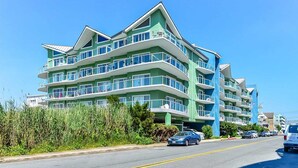 A multi-story hotel with balconies, a clear sky, and a road with cars. - 🏖️Serene Bayfront Bliss - Pristine 3 Bed/3Bath condo🏖️ (Ocean City)