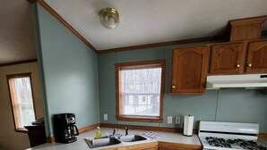 A kitchen with wooden cabinets, a white stove, and a refrigerator. - Cozy little home located in the Finger Lakes (Dundee)