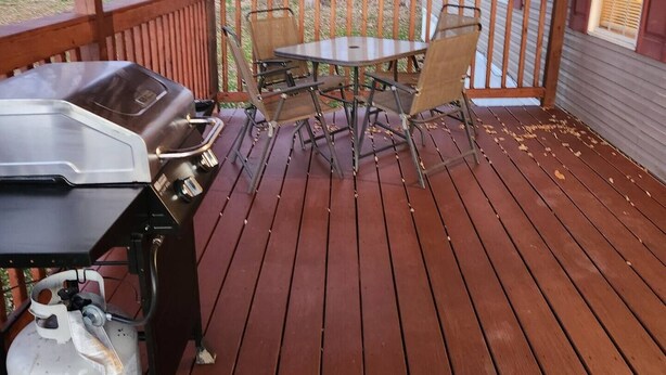 A wooden deck with a grill and table set up for outdoor dining. - Cozy little home located in the Finger Lakes (Dundee)