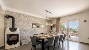 Un espace repas moderne avec un mur en briques, un poêle à bois et une table dressée pour six personnes.
