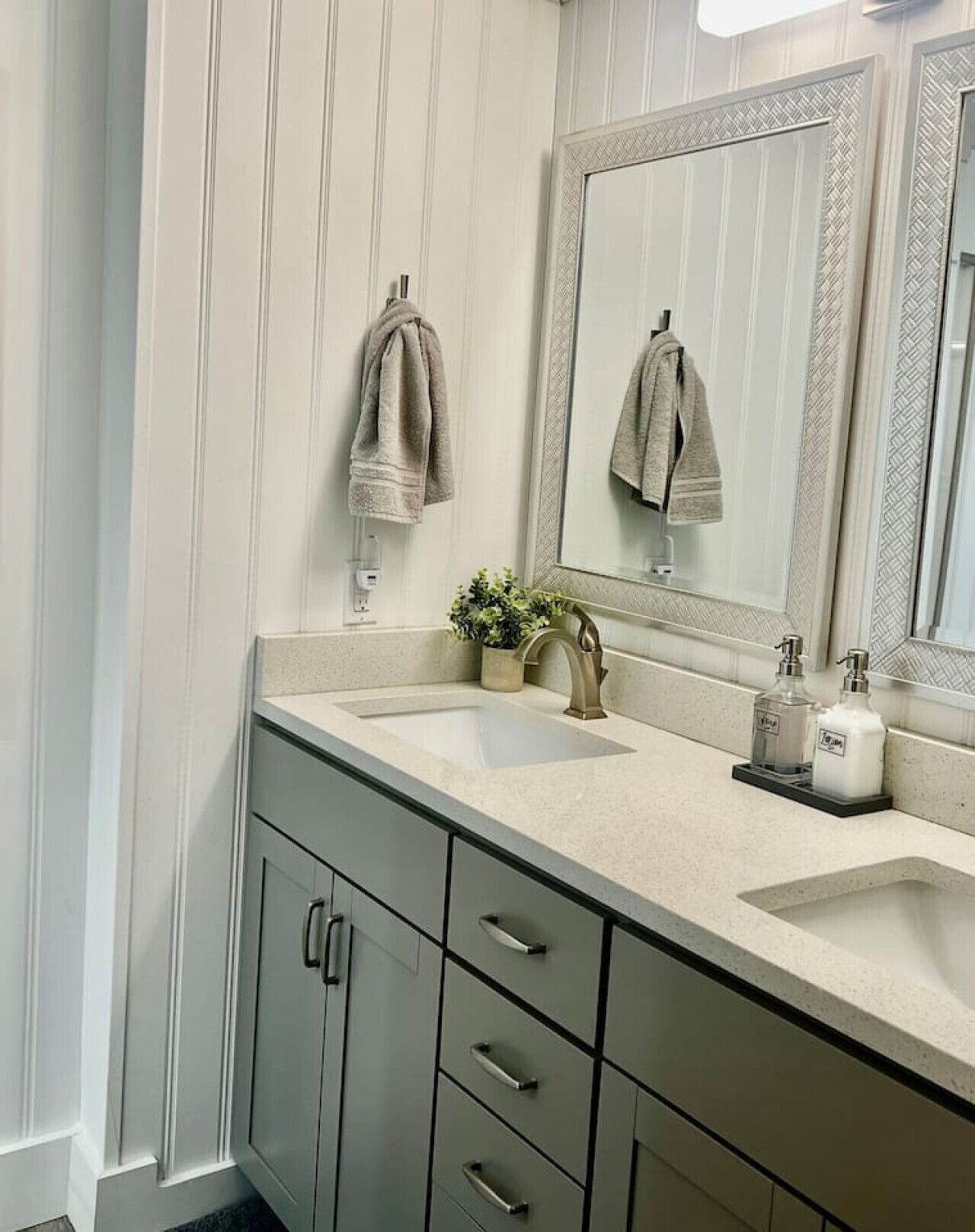 A bathroom with a sink, mirror, towel rack, and a plant.