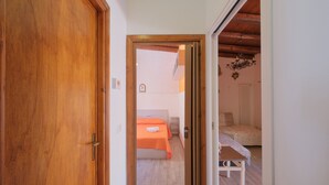 A bedroom with a bed, a bedside table, and a wooden door. - Terrazza dei Coralli (Cefalù)