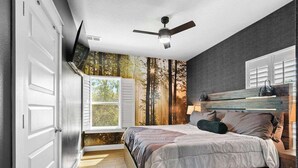 A bedroom with a bed, a ceiling fan, a window, and a wall with a forest mural. - THe Pirates Hideout - slide•gameroom•ada•elevator•rockwall (Pensacola)