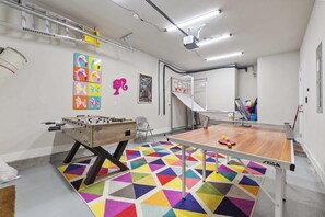 A room with a foosball table, ping pong table, colorful geometric carpet, and a ladder. - indoor playground•rockwall•gameroom•ada•elevator (Pensacola)