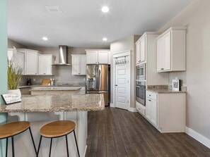 A modern kitchen with white cabinets, stainless steel appliances, and a granite countertop. - indoor playground•rockwall•gameroom•ada•elevator (Pensacola)