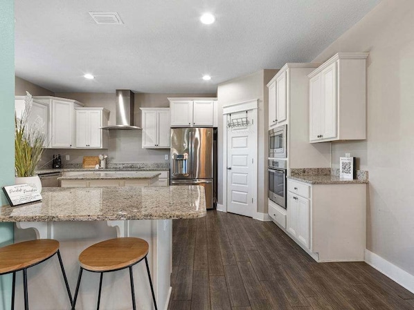 A modern kitchen with white cabinets, stainless steel appliances, and a granite countertop.