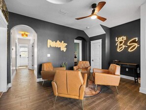 A modern interior with a dark wall, a ceiling fan, and a sign that reads 'Let's B-S.' - indoor playground•rockwall•gameroom•ada•elevator (Pensacola)