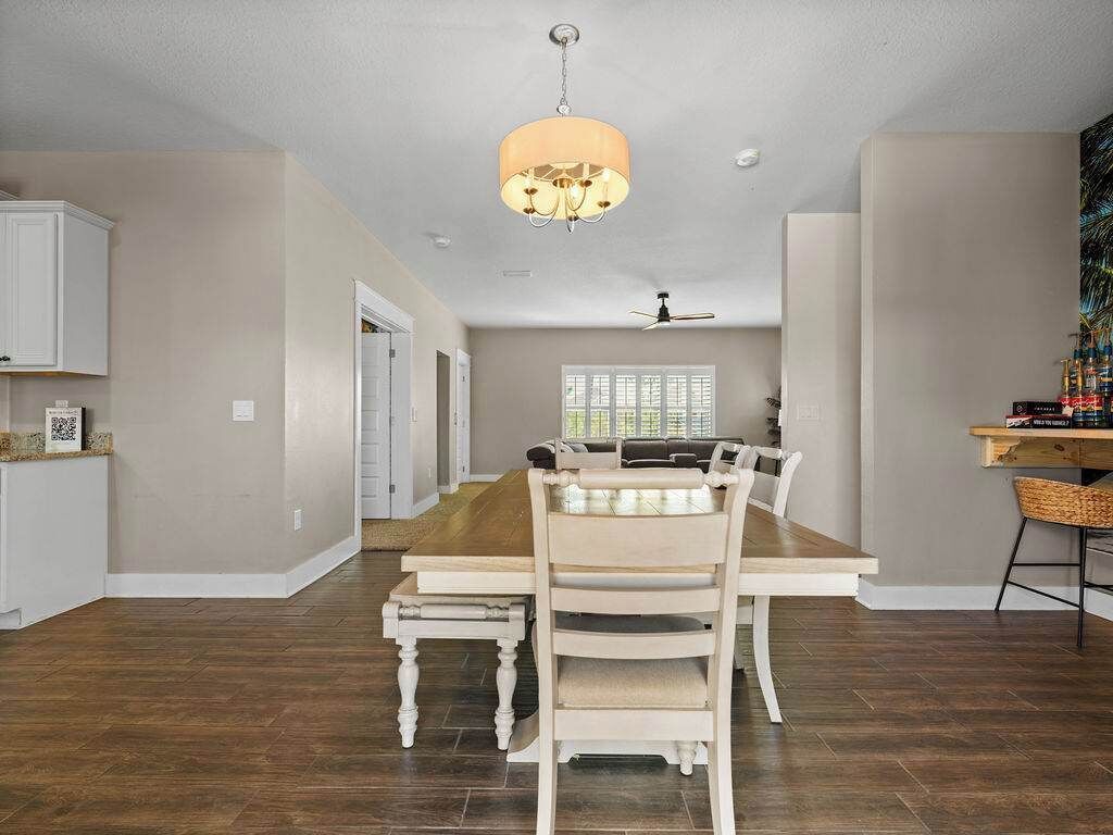 Un'ampia sala da pranzo con un tavolo e sedie in legno, un lampadario e una ventola a soffitto.