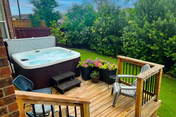 Enjoy relaxing in the hot tub surrounded by lush landscaping and deck seating.