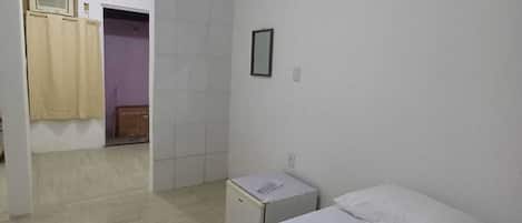 A simple, clean room with a bed, a small bedside table, and a wardrobe.