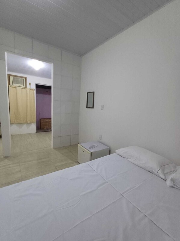 A simple, clean room with a bed, a small bedside table, and a wardrobe. - Pousada Estelita Ponta de Areia Itaparic (Itaparica)