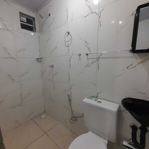 A bathroom with white marble walls, a toilet, a sink, and a shower area. - Pousada Estelita Ponta de Areia Itaparic (Itaparica)