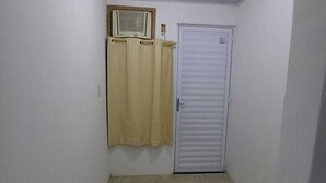 A narrow hallway with a white door and a beige curtain. - Pousada Estelita Ponta de Areia Itaparic (Itaparica)