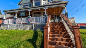 A two-story house with a porch and a staircase leading to the front door. - Harris House 4 | On Hospital Campus (Duluth)