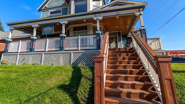 Ein zweistöckiges Haus mit einer Veranda und einer Treppe zum Eingang.