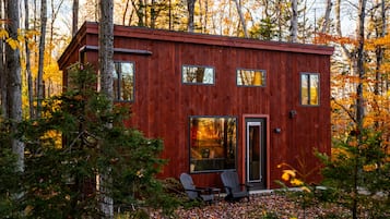 A cabin with a wooden exterior, multiple windows, and a door.