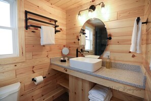 A wooden cabin bathroom with a sink, mirror, towel rack, and toilet. - Luxury Cabin #3 Hot Tub, Kayaks, Paddle Boards, Private Fire Pit (Cavendish)