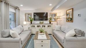 Un salon moderne comprenant deux canapés, une table basse, un téléviseur et un meuble agrémenté d’objets décoratifs.