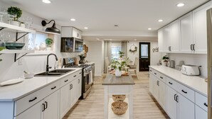 Une cuisine moderne avec des meubles blancs, un îlot central et un coin repas comprenant une table et des chaises.