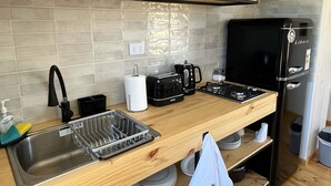 Una cocina moderna con un lavamanos de acero inoxidable, encimera de madera y un refrigerador negro.