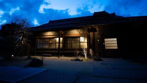 Un bâtiment japonais traditionnel, doté d’un toit recouvert de tuiles, de grandes fenêtres et d’une cour intérieure en gravier.