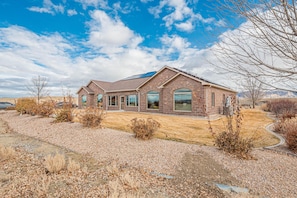 A two-story house with a brick exterior, large windows, and a solar panel on the roof. - Hansel: Space, BLM Backdrop & BBQ Vibes! (Grand Junction)