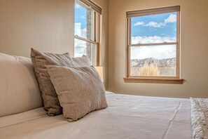A bedroom with a bed, two pillows, a window, and a view of mountains. - Hansel: Space, BLM Backdrop & BBQ Vibes! (Grand Junction)