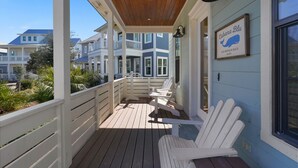 Une véranda couverte avec des fauteuils Adirondack blancs, un plafond en bois et une enseigne indiquant : « Rebecca Blu, plage de Blue Mountain ».