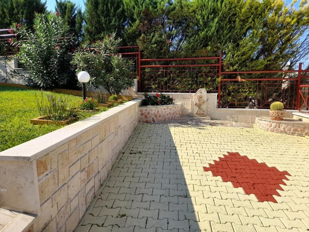 A paved courtyard with a red star pattern, a stone wall, and a metal gate.