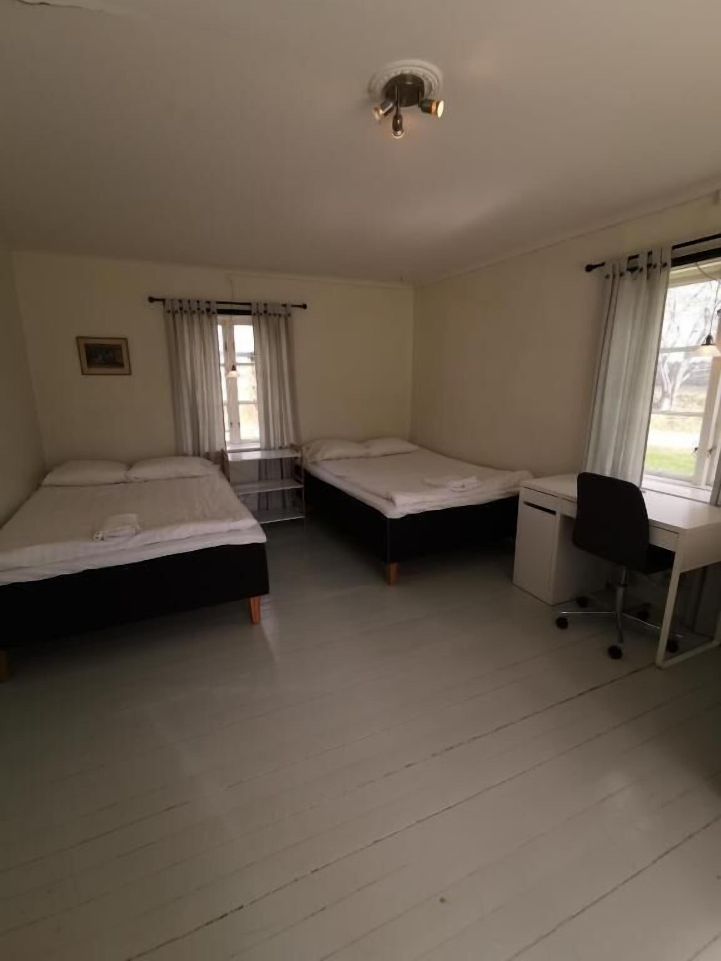 Une chambre avec deux lits simples, un bureau et une chaise.