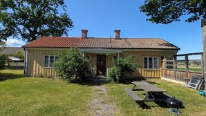 A single-story house with a red-tiled roof, a front porch, and a small garden area with a picnic table and grill. - Västervik rum och stugor (Vastervik)