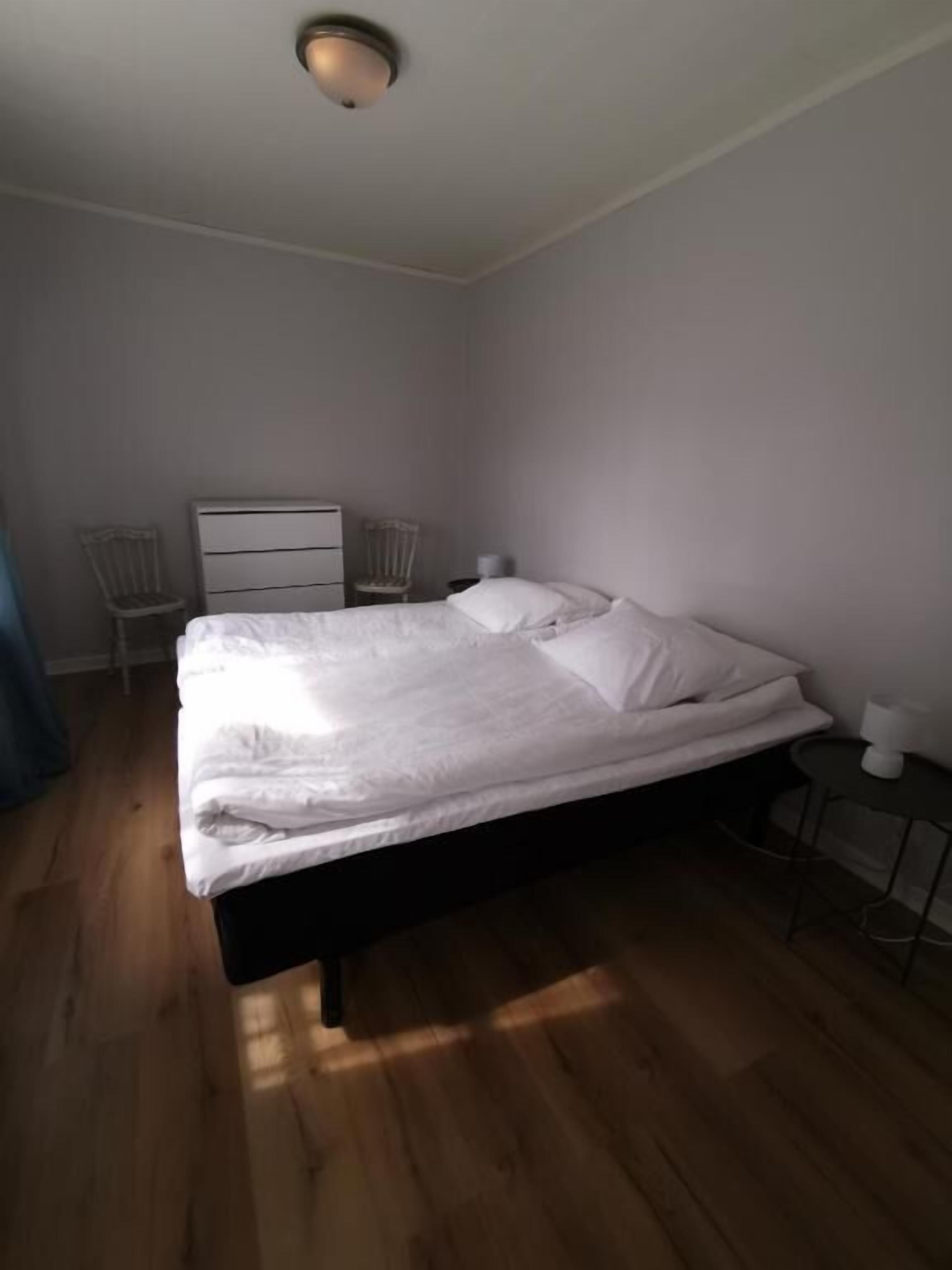 A bedroom with a bed, two chairs, a dresser, and a small table.