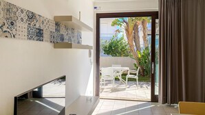 A modern room with a tiled floor, a white desk, a chair, a small table, and a view of an outdoor patio with a table and chairs. - Nice home in Marina di Ragusa with WiFi (Marina di Ragusa)