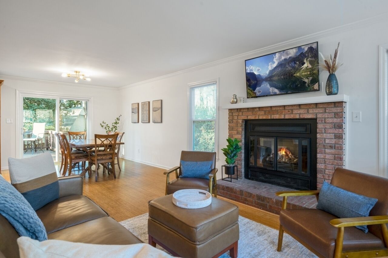 A living room with a fireplace, a dining area, and a view of the outdoors.