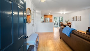 Una sala de estar moderna con un sofá de cuero marrón, un banco y una zona de comedor con muebles de madera.