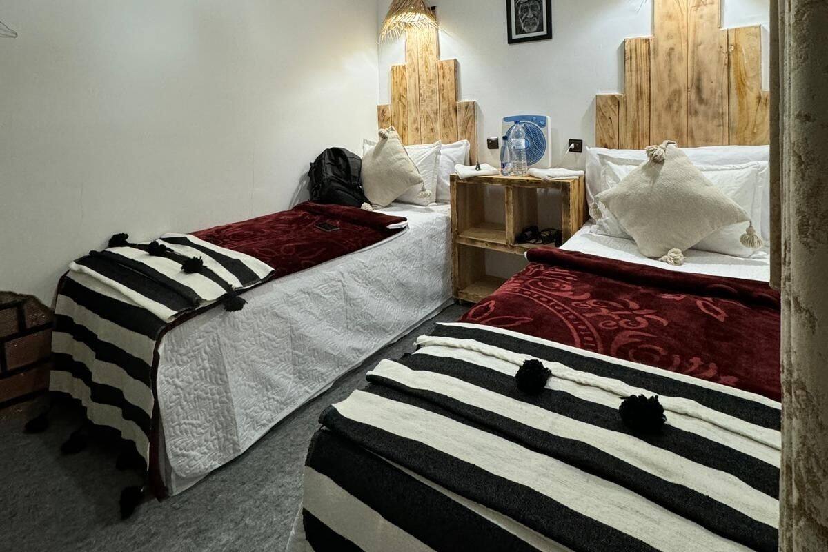 Un dormitorio con dos camas, un ventilador de techo y una lámpara fijada a la pared.
