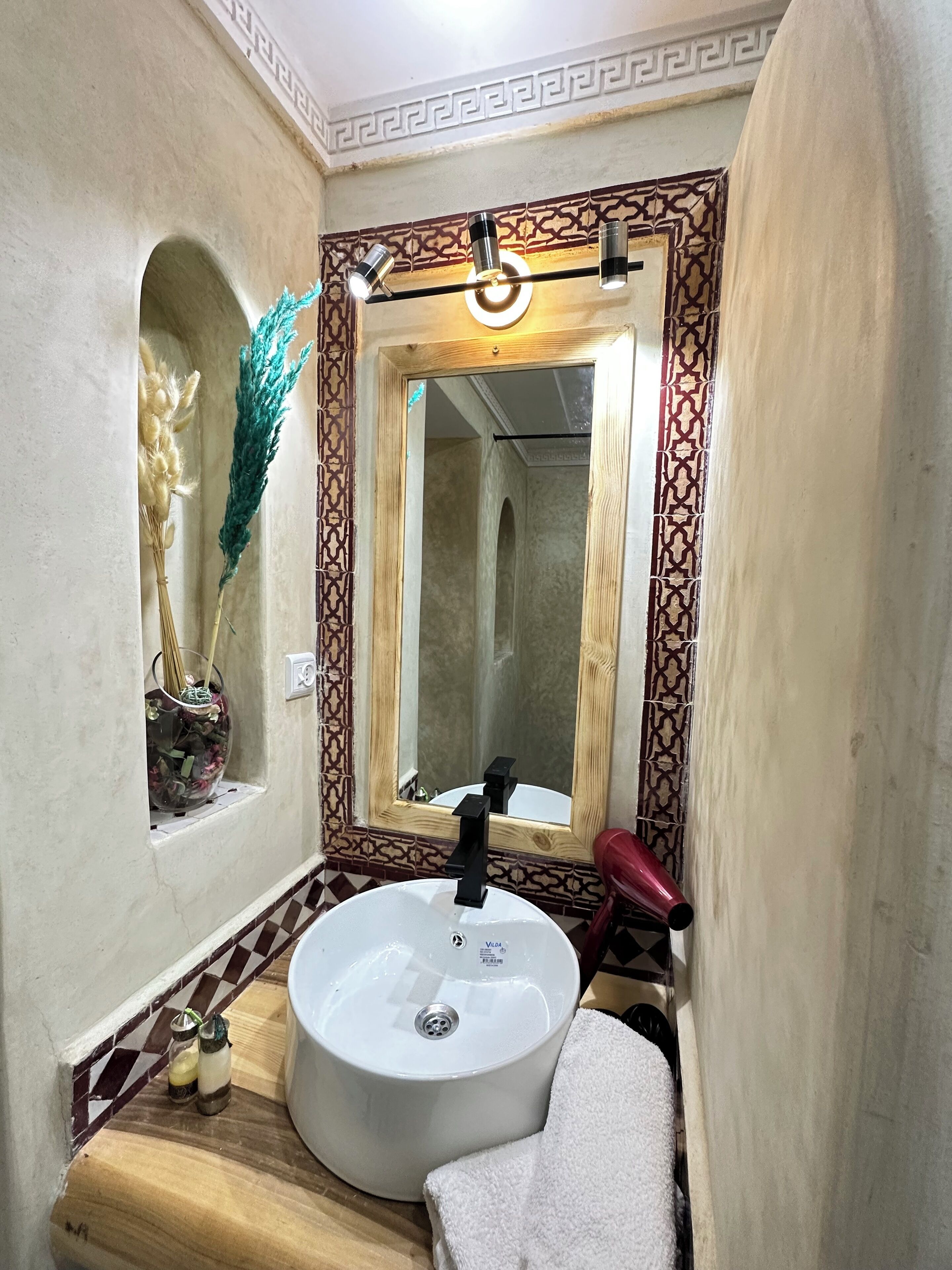 Un baño con un lavabo redondo, un espejo con marco decorativo y una toalla sobre el mostrador.