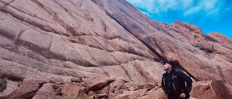 Une personne se tient debout sur un terrain rocheux, avec une chaîne de montagnes en arrière-plan.