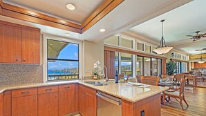 Une cuisine spacieuse avec des meubles en bois, un grand îlot central et une vue sur l’extérieur.