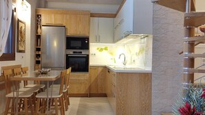 A compact kitchen with wooden cabinets, a stainless steel refrigerator, a built-in oven, and a modern sink area.