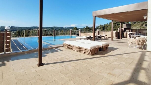 A rooftop pool area with lounge chairs and a covered seating area.