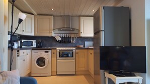 A compact kitchen with a washing machine, microwave, stove, and refrigerator. - Appartement vue sur mer (Soulac sur Mer)