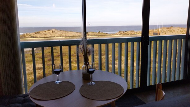 A table with two wine glasses and a vase on a balcony overlooking a beach. - Appartement vue sur mer (Soulac sur Mer)