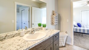 A bathroom with a marble sink, dark wooden cabinets, a towel rack, and a ceiling fan. - Colorado Springs Family Home ~ 10 Mi to Downtown! (Colorado Springs)