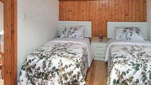 Ein Schlafzimmer mit zwei Betten, Holzwänden und einer weißen Decke.