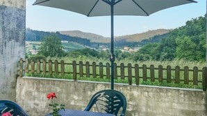 Ein Balkon mit Blick auf eine ländliche Landschaft, einem Tisch mit Stühlen und einem Blumentopf.