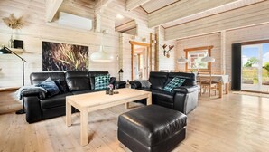 A spacious living area with a wooden ceiling, a large painting, a dining table with chairs, and a view through a sliding glass door. - Beautiful home in Hemmet with kitchen (Hemmet)
